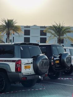 several cars parked in a parking lot with palm trees