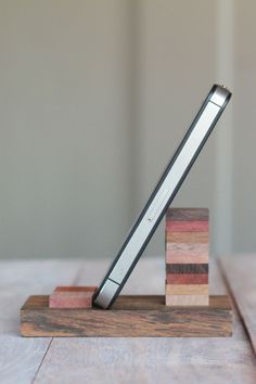 a wooden block with a metal pen on it sitting on top of a wood stand