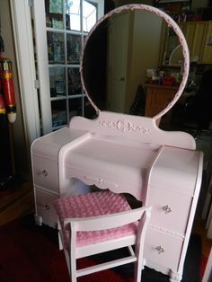 a white dressing table with a mirror and stool