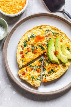 an omelet with avocado and cheese is on a plate next to other ingredients