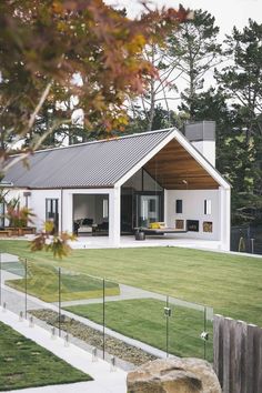 a white house with an open porch in the front yard and large grass area next to it