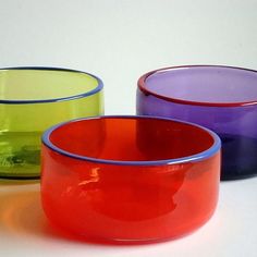 three different colored glass bowls sitting next to each other on top of a white surface