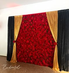 a red and black backdrop with gold drapes on the side is decorated with roses