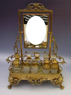 there is a mirror and some jars in front of it on a stand with an ornate gold frame