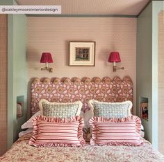 a bed with two lamps on either side of it and pink bedspread in front of the headboard