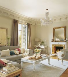 a living room filled with furniture and a chandelier hanging from the ceiling over a fire place