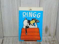 a sign that says ring on the side of a wooden wall with a mouse in it