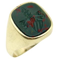 This 14k gold Edwardian intaglio signet ring contains an esoteric image—a unique family crest with mysterious imagery. Carved into bloodstone, a striped shield sits on a diagonal, with a scroll looming above it. It is topped with a crown, a pine tree, and a tiny animal—perhaps a horse, coyote, or deer—who seems to shape shift each time it is looked at under the loop. The ambiguity of the image is sure to evoke thought. The bezel set bloodstone is beautiful and deep, with speckles of red "blood” across the dark green stone. The ring is marked with 585 for 14k gold. It weighs 10.9 grams. The intaglio measures approximately 1/2” x 5/8”. The ring also could be used as a wax seal! Ring size 10.25. Can be resized and would look great on either a man or woman. Red Blood, Family Crest, Pinky Ring, Size 10 Rings, Pine Tree, Green Stone, Wax Seals, Signet Ring, Deer