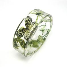 a glass bracelet with butterflies and flowers on the inside, sitting in front of a white background