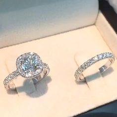 two engagement rings sitting in a box on display