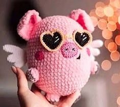 a hand holding a pink stuffed animal with heart shaped glasses on it's face