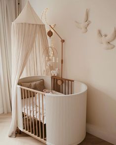 a white crib in the corner of a room next to a wall with birds on it