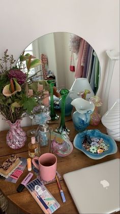 a mirror sitting on top of a wooden table next to a vase filled with flowers