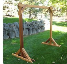 two wooden frames sitting on top of green grass next to a stone wall and trees