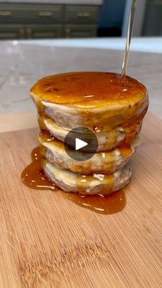 a stack of pancakes sitting on top of a wooden cutting board covered in caramel syrup