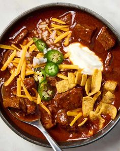 a bowl filled with chili, cheese and meat