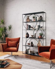 a living room with two orange chairs and a shelf filled with vases on it