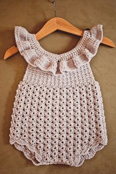 a crocheted baby dress hanging on a wooden hanger with the words baby dress written below it