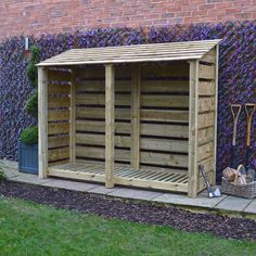 a wooden storage shed sitting next to a brick wall with purple flowers growing on it