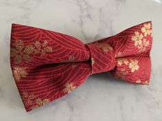 Upgrade your wardrobe in style with this stunning red and gold floral pattern bow tie. Perfect gift for him, this unique adjustable bow tie will elevate any occasion including weddings, birthdays and anniversaries. Comes pre-tied. Elegant Red Bow For Gift, Elegant Red Bow Tie As Gift, Gold Bow With Ties For Gifts, Red Bow With Butterfly Knot For Party, Elegant Red Bow With Butterfly Knot, Elegant Red Adjustable Bow, Elegant Red Bow Tie Adjustable, Red Adjustable Bow Tie With Bow Tie Back, Adjustable Red Bow Tie For Wedding