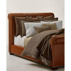 a brown leather bed frame with pillows and blankets