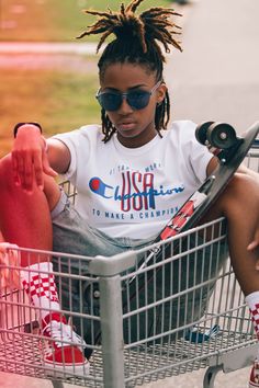 a young woman sitting in a shopping cart with her skateboard on the handlebars