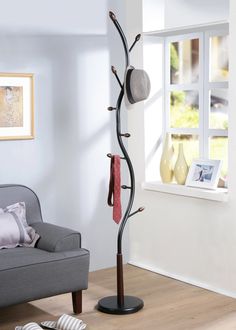 a living room with a couch and a coat rack on the floor in front of a window