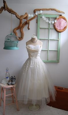 a dress is on display in front of a birdcage and other items that are hanging from the wall