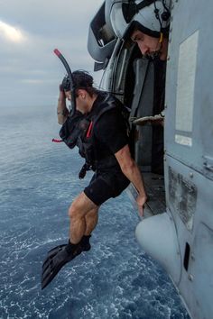 a man in scuba gear climbing out of an airplane