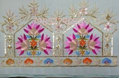 an embroidered wall hanging with flowers and leaves in gold, pink, orange and blue colors