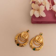 Description: Step into minimal sophistication with our exquisite antique gold-plated Chandbali earrings. Delicately adorned green kempu stones accentuating the Lakshmi temple coin, it exudes timeless allure and sophistication in every detail. Perfect for enhancing any ensemble, these earrings effortlessly harmonize with other antique jewelry for a refined and coordinated look. Details & Specification: Materials used: Brass Alloy with Antique Gold Plating Weight - 10.2 gm Length - 3.5 cm Make it Lakshmi Coin Earrings Gold, Temple Jewelry Earrings, Green Stone Studs Gold, Lakshmi Earrings Gold, Kasu Earrings Gold, Chandbali Earrings Gold Antiques, Gold Earrings Designs Indian, Green Stone Gold Ring, Green Stone Earrings Gold