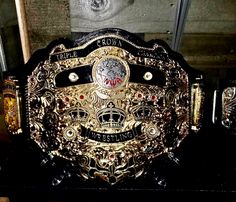 a gold and black wrestling belt sitting on top of a wooden shelf in a room