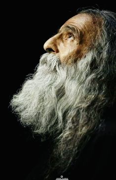 an old man with long grey hair and a beard is looking up at the sky