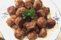 a white plate topped with meatballs covered in parsley