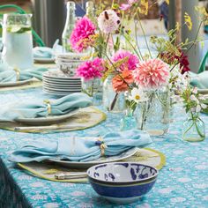 the table is set with blue and white plates, napkins, and vases filled with flowers