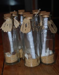 four glass jars with sand and paper in them