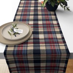 a plaid table runner with a place setting on it and a potted plant next to it