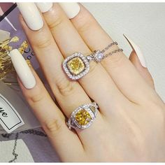 a woman's hand with three different rings and one yellow diamond on the ring