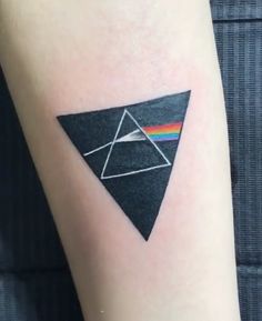 a small triangle tattoo on the right arm with a pink floyd rainbow in the center