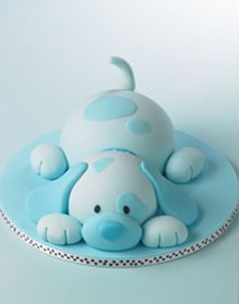 a blue and white cake with a dog on it's head sitting on a plate