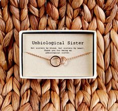 a necklace with two interlocked rings on it sitting in front of a box