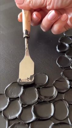 a person holding a spatula over some chocolate circles on a table with a knife sticking out of it