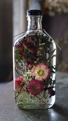 a bottle filled with flowers sitting on top of a table