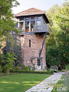 an image of a house that is in the middle of some grass with trees and bushes around it