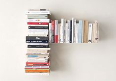 a bookshelf filled with lots of books on top of a white table next to a wall