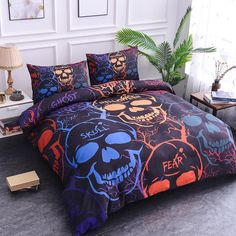 a bed with colorful skulls on it in a room next to a lamp and plant