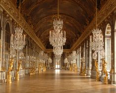 an ornate hall with chandeliers and mirrors on the walls is shown in gold