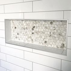 a bathroom with white tile and hexagonal tiles on the wall, along with a toilet paper dispenser