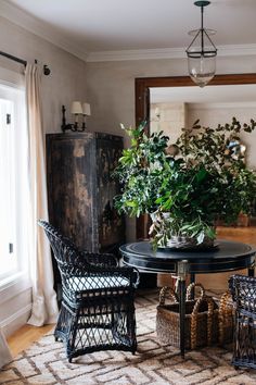 two wicker chairs sitting next to a table with plants on it in front of a mirror