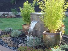 a water fountain in the middle of a garden with potted plants next to it